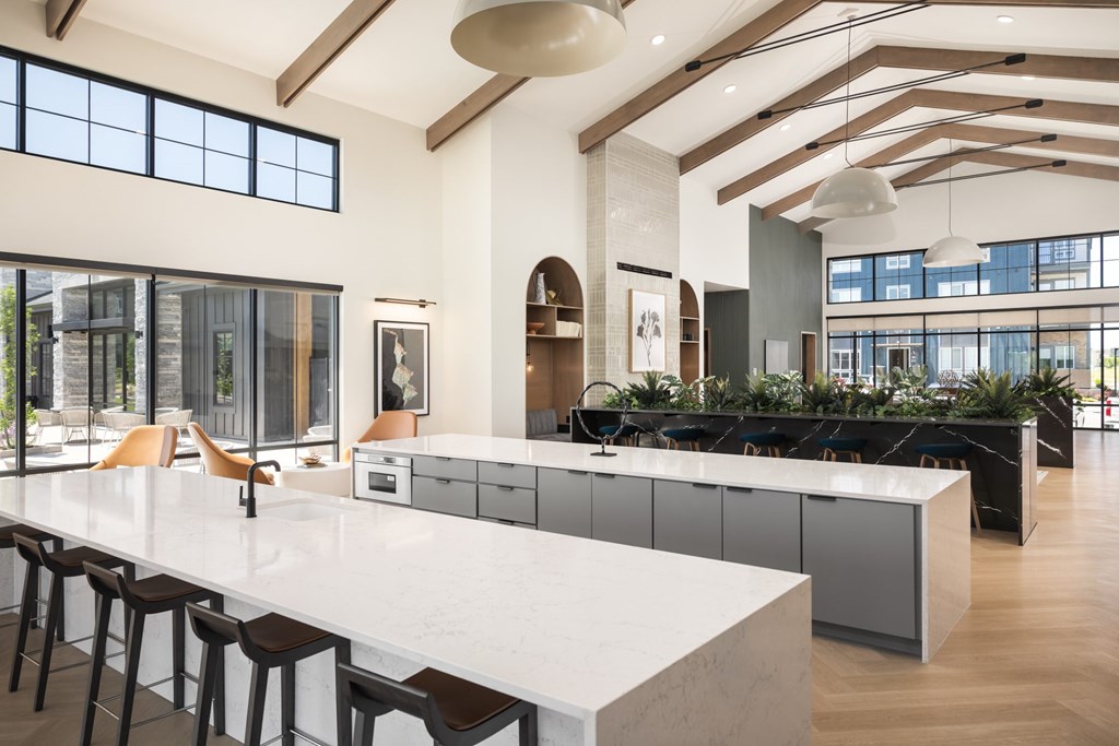 A modern kitchen with a long white island and bar stools.