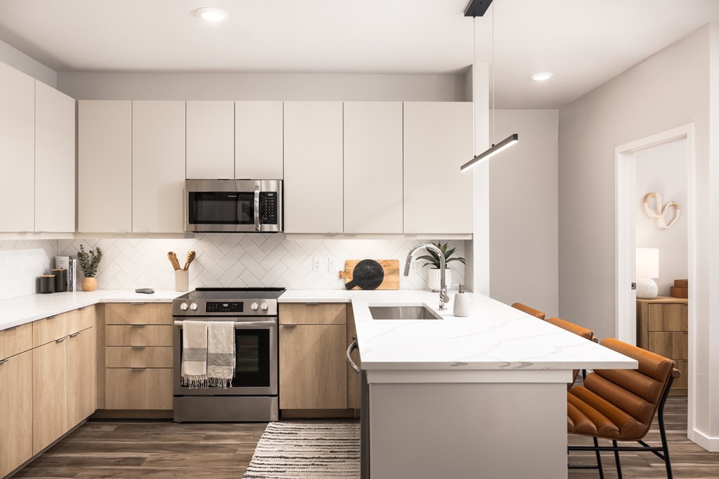 A modern kitchen with a white countertop and wooden cabinets.