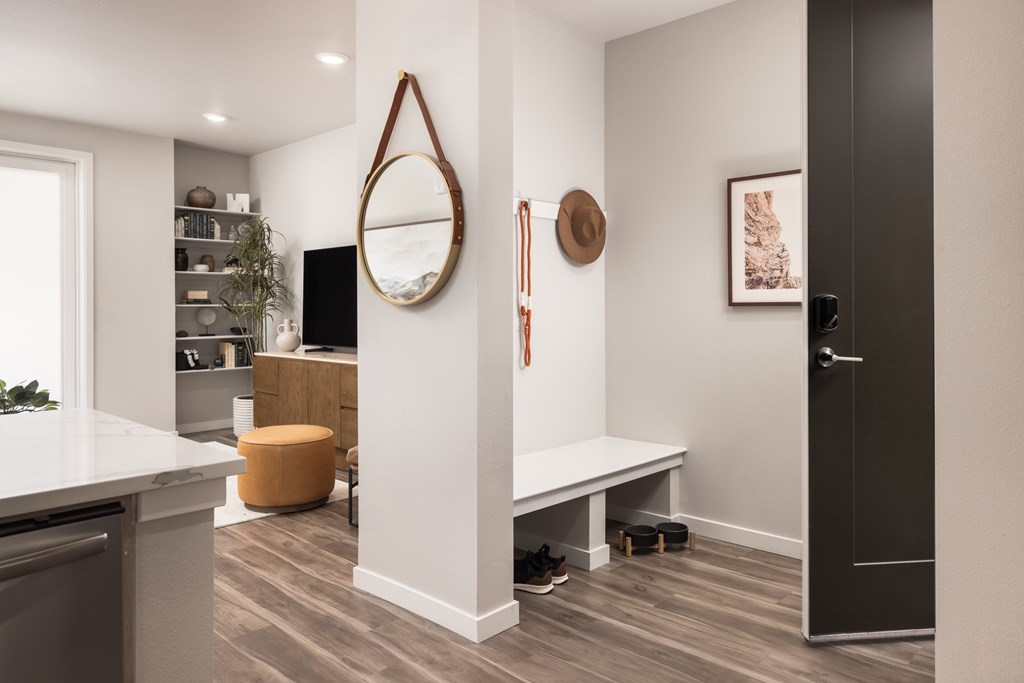 A modern kitchen with a white countertop and a round mirror on the wall.