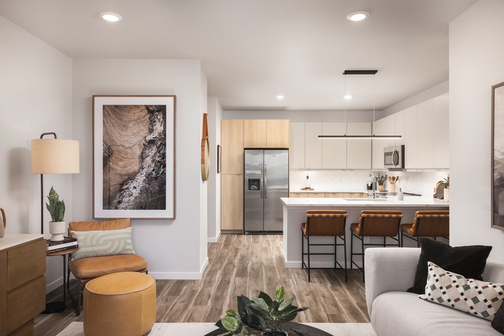 A modern living room with a kitchen in the background.