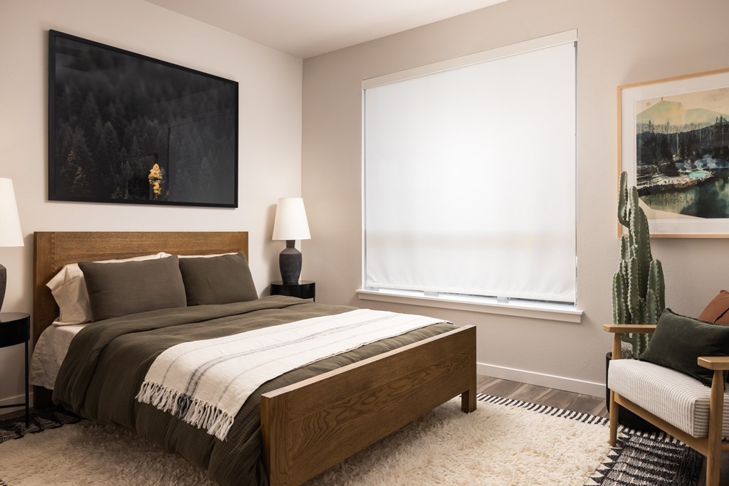 A bedroom with a large bed, a chair, and a painting on the wall.