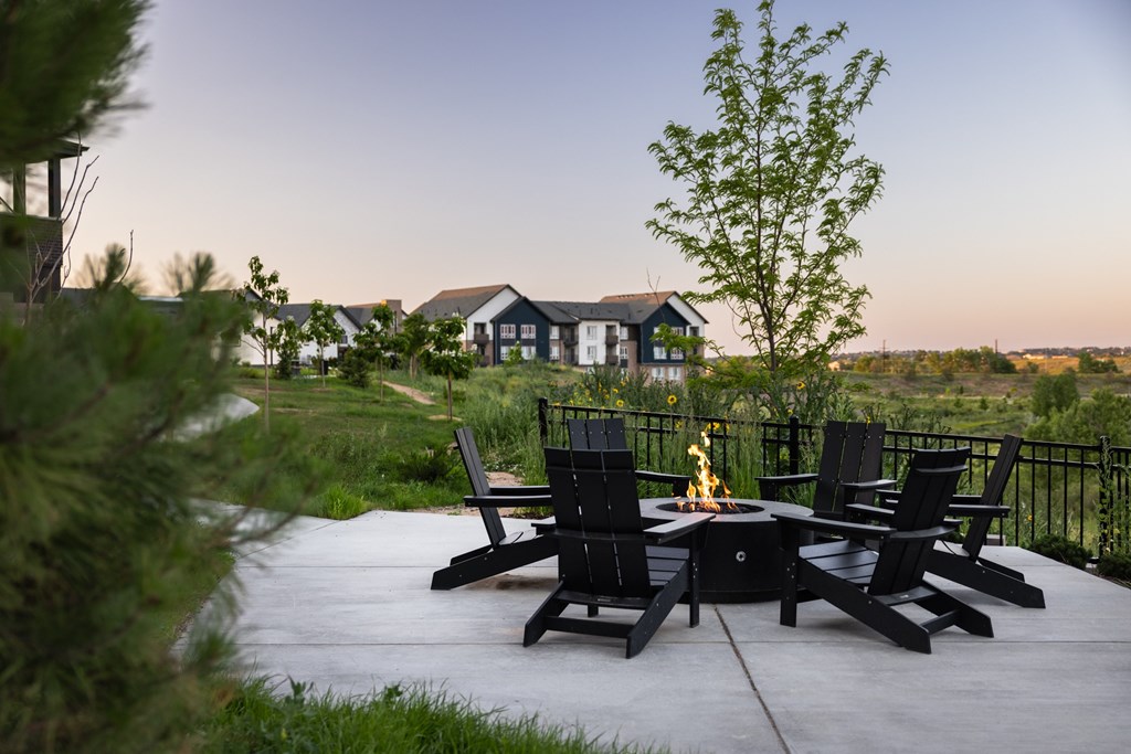 A patio with chairs and a fire pit in the middle.