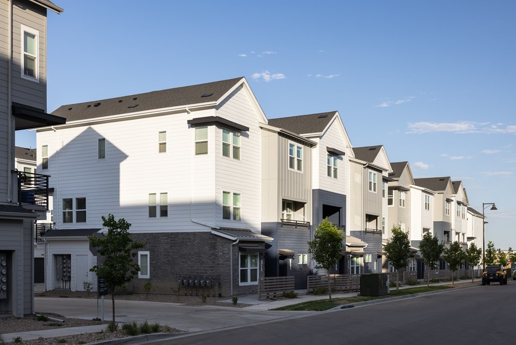 A row of modern houses with white exteriors and dark roofs.