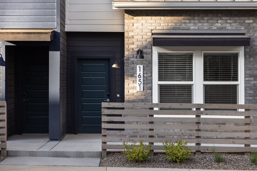 A modern house with a black door and a window with white blinds.