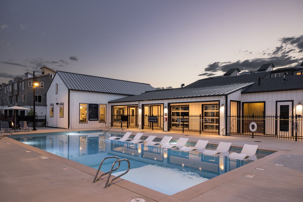 A swimming pool with lounge chairs and a building in the background.