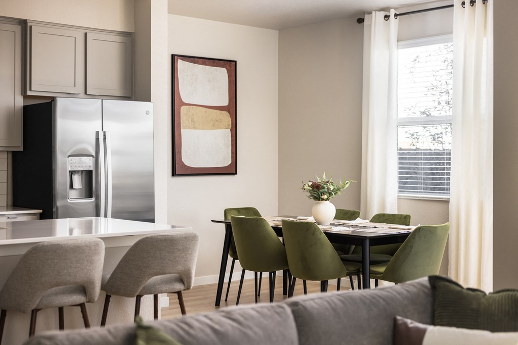 a living room and dining room with a table and chairs and a refrigerator