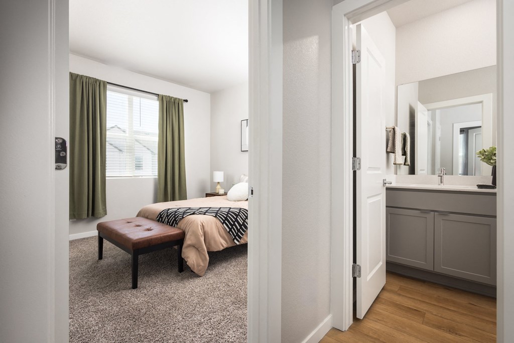 a bedroom with a bed and a mirror and a bathroom