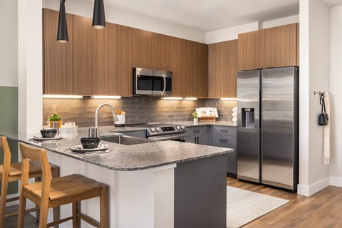 A modern kitchen with wooden cabinets and a grey island.