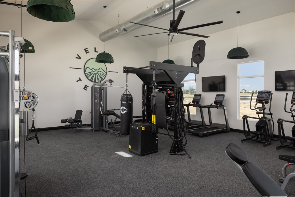 a workout room with weights and cardio equipment and a clock on the wall