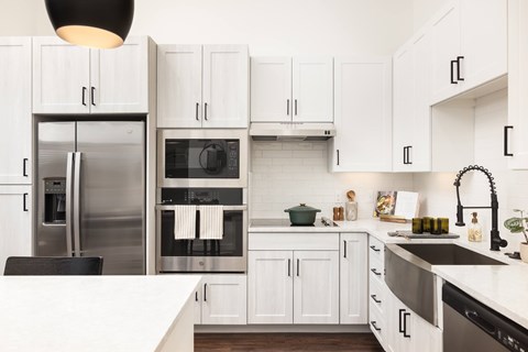 A modern kitchen with white cabinets and stainless steel appliances.