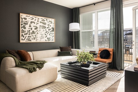 A living room with a white couch, a coffee table, and a large abstract painting on the wall.