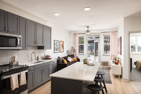A modern kitchen with dark grey cabinets and a white countertop.