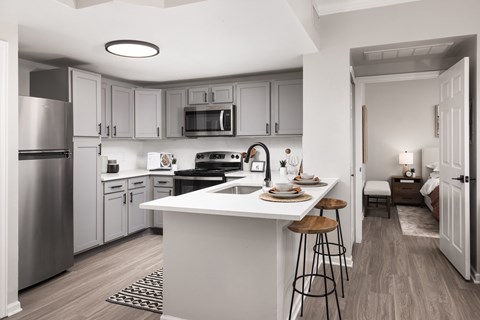 A modern kitchen with a white island and stools.