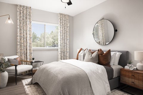 A bedroom with a large bed, a chair, a table, a lamp, and a mirror.