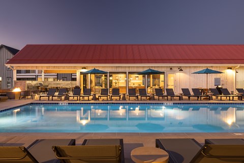 A pool with chairs around it and a building in the background.