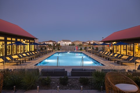A large outdoor swimming pool surrounded by lounge chairs and plants.