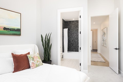 A bedroom with a white bed and a painting on the wall.