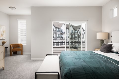 A bedroom with a large bed and a view of a building outside the window.