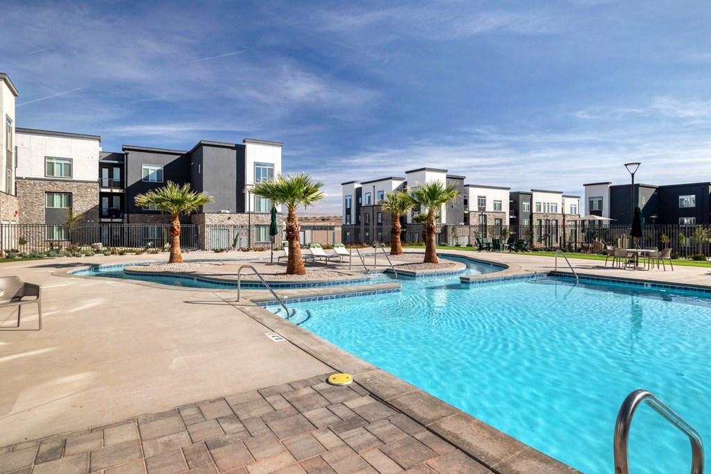a swimming pool with palm trees and apartments in the background