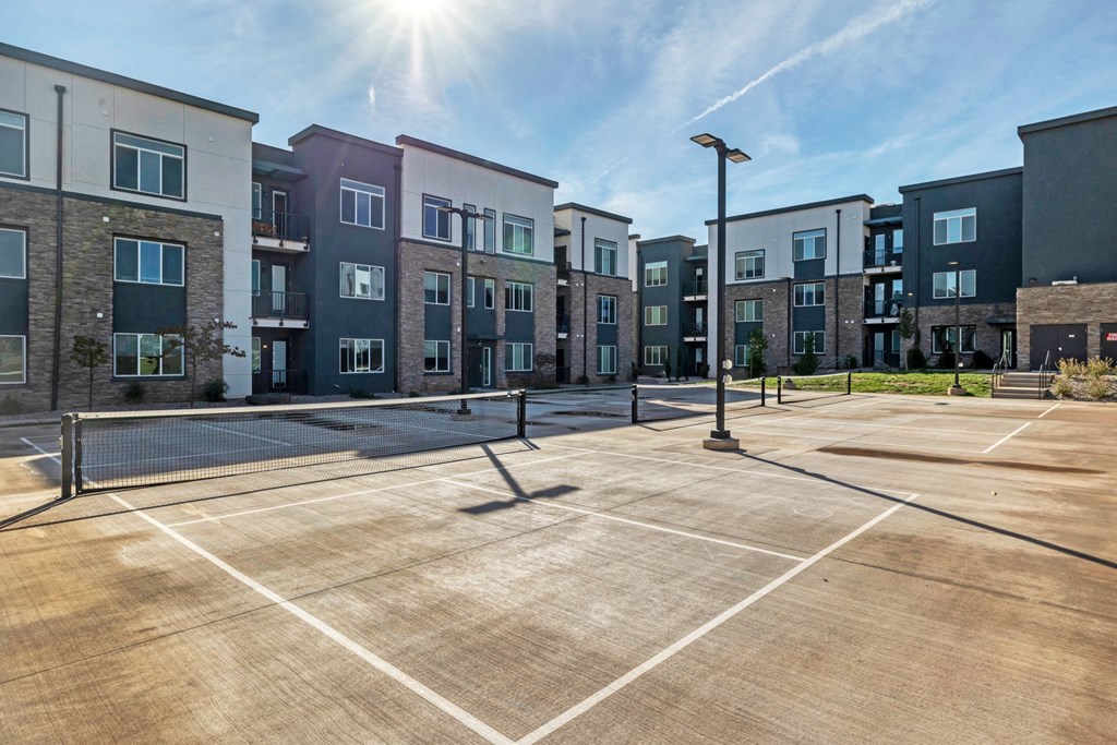 an empty tennis court in front of an apartment building