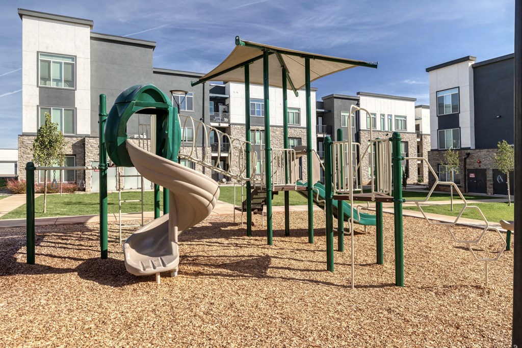 a playground with a slide and climbing equipment in front of apartments