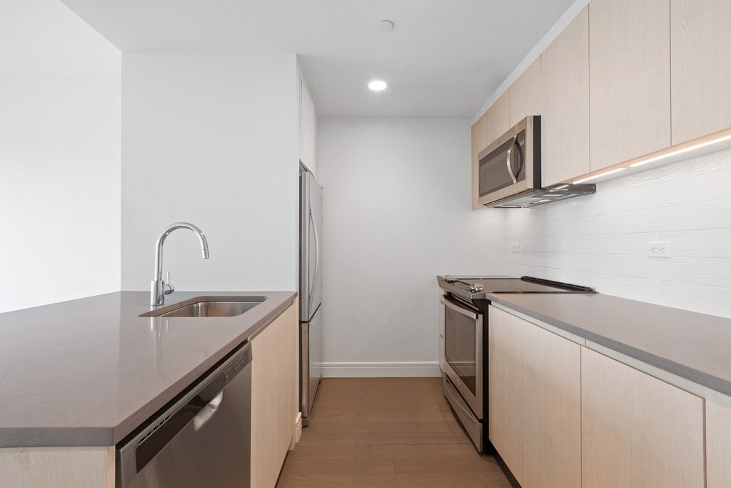 an empty kitchen with stainless steel appliances and a sink