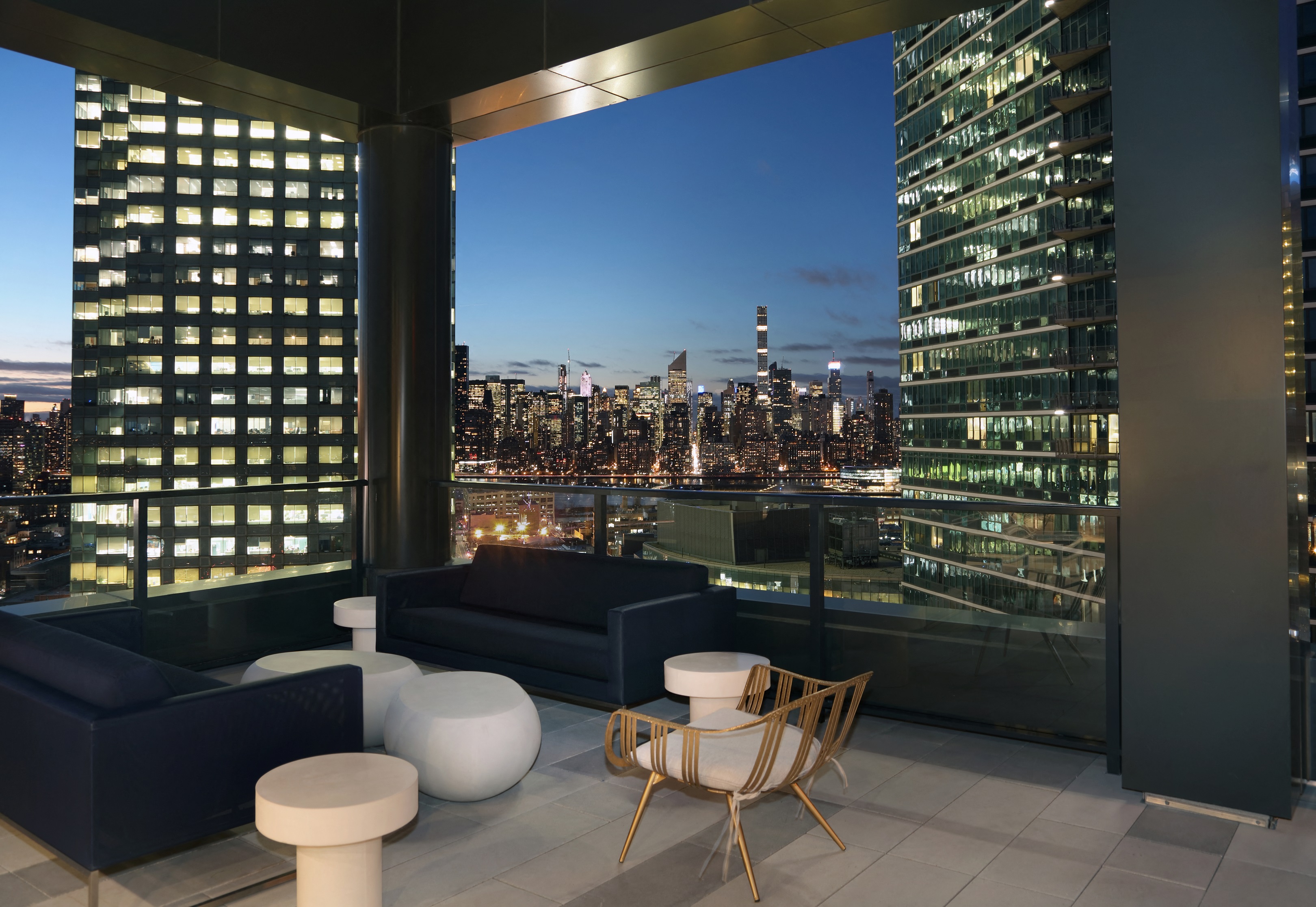 a view of the city skyline from a terrace with couches and chairs