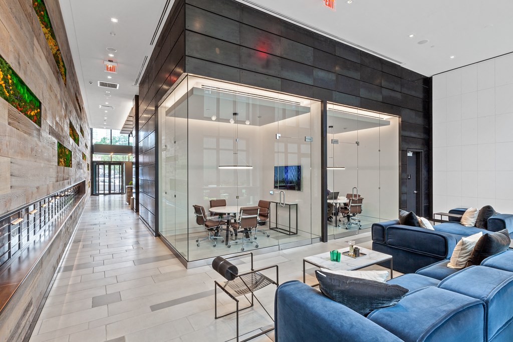 a living room with blue couches and a glass walled room with a table