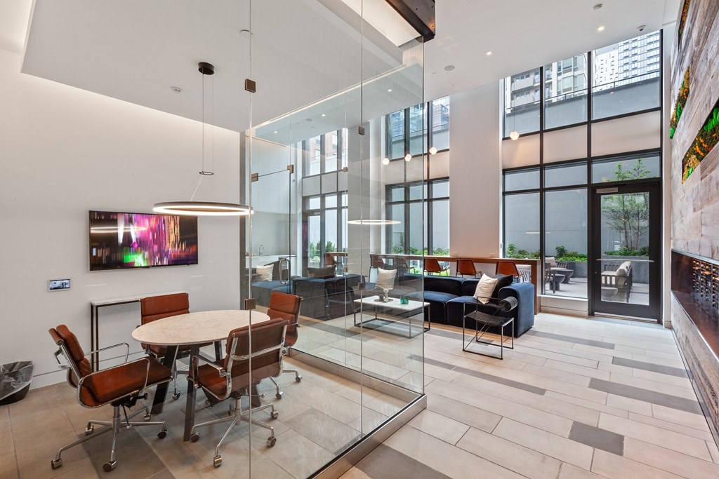 a communal area with a table and chairs and a large window