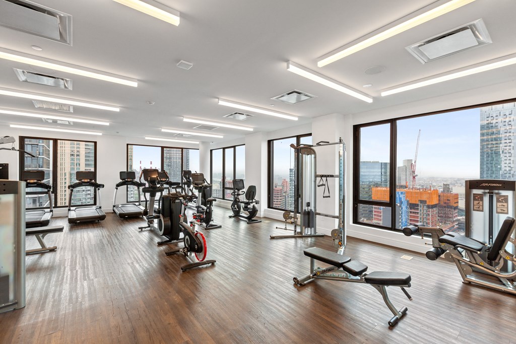 a gym with exercise equipment and window views of the city