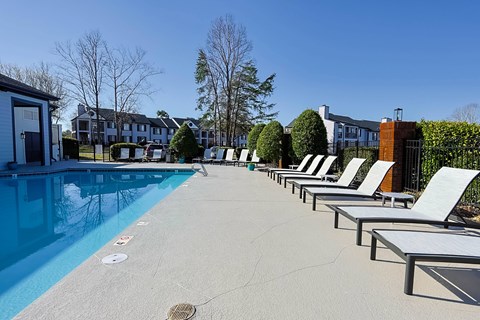A pool with sun loungers and a building in the background.