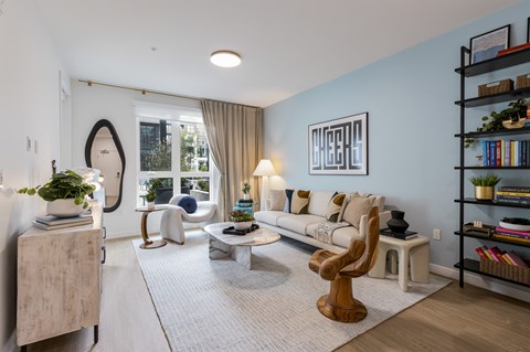 A living room with a white sofa, a wooden chair, and a large mirror on the wall.