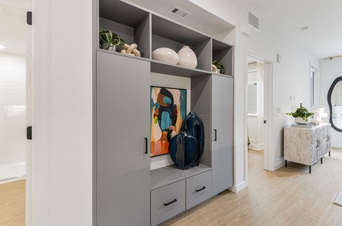 A grey cabinet with a painting on it and a potted plant on the side table.