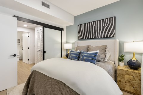 A bedroom with a large bed and a striped picture on the wall.