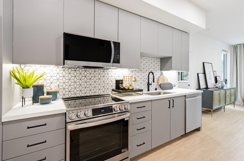 A modern kitchen with a black microwave above the stove.