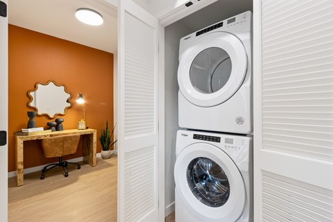 A white washing machine is stacked on top of another white washing machine in a laundry room.