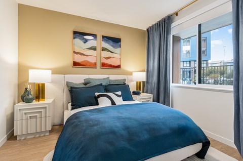 A bedroom with a large bed and a painting on the wall.