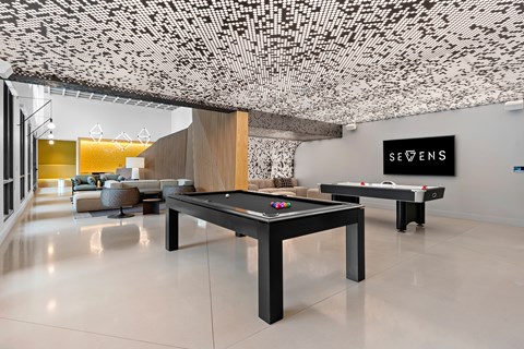 A room with a pool table and a sign that says "SEVENS".