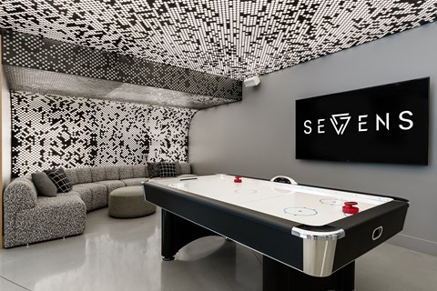 A pool table in a room with a black and white patterned ceiling.