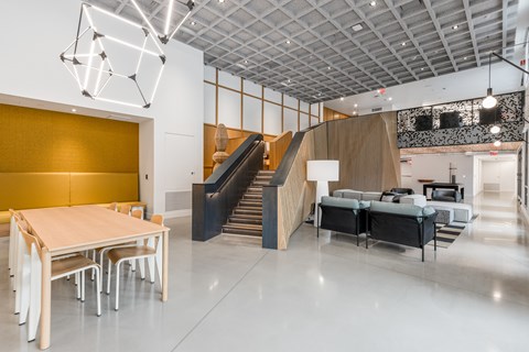 A modern interior with a wooden table and chairs, a staircase, and a geometric light fixture.