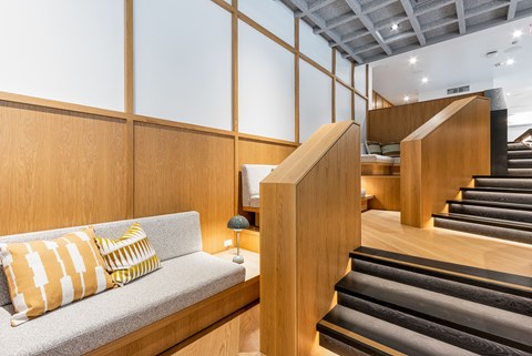 A living room with a grey couch and a wooden staircase.