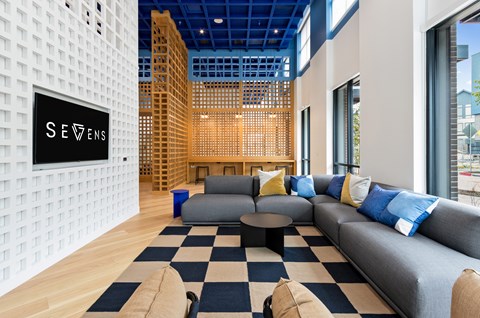 A modern living room with a checkered rug and a grey sofa.