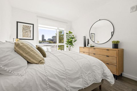 a bedroom with a bed and a mirror and a window