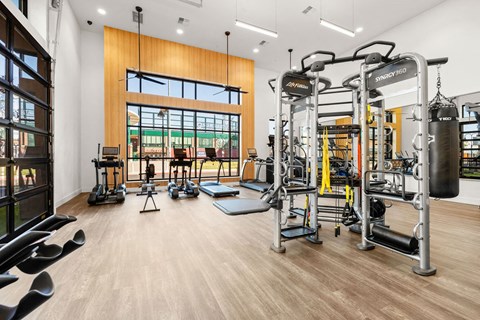 a gym with weights and cardio equipment and a large window