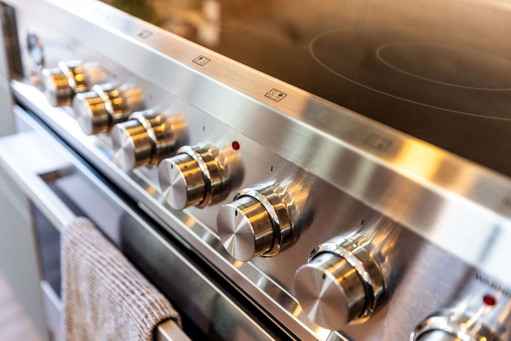 A close-up of a stainless steel oven with five knobs.