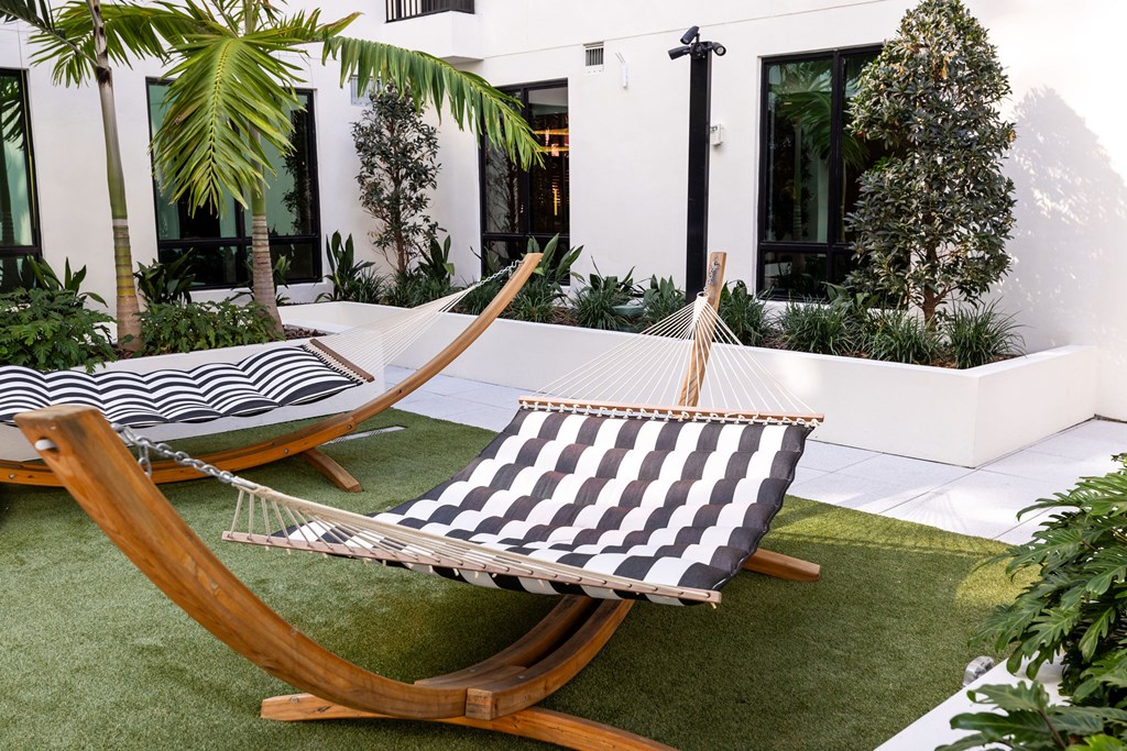 Two black and white striped hammocks are suspended between two wooden poles.