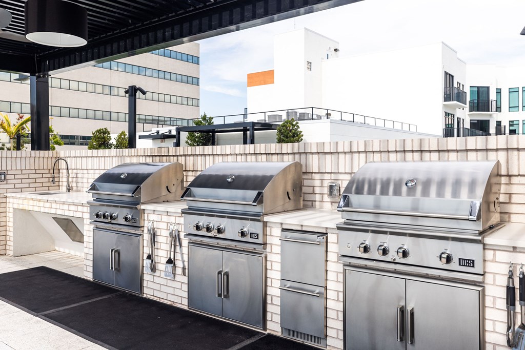 A row of outdoor grills are lined up on a patio.
