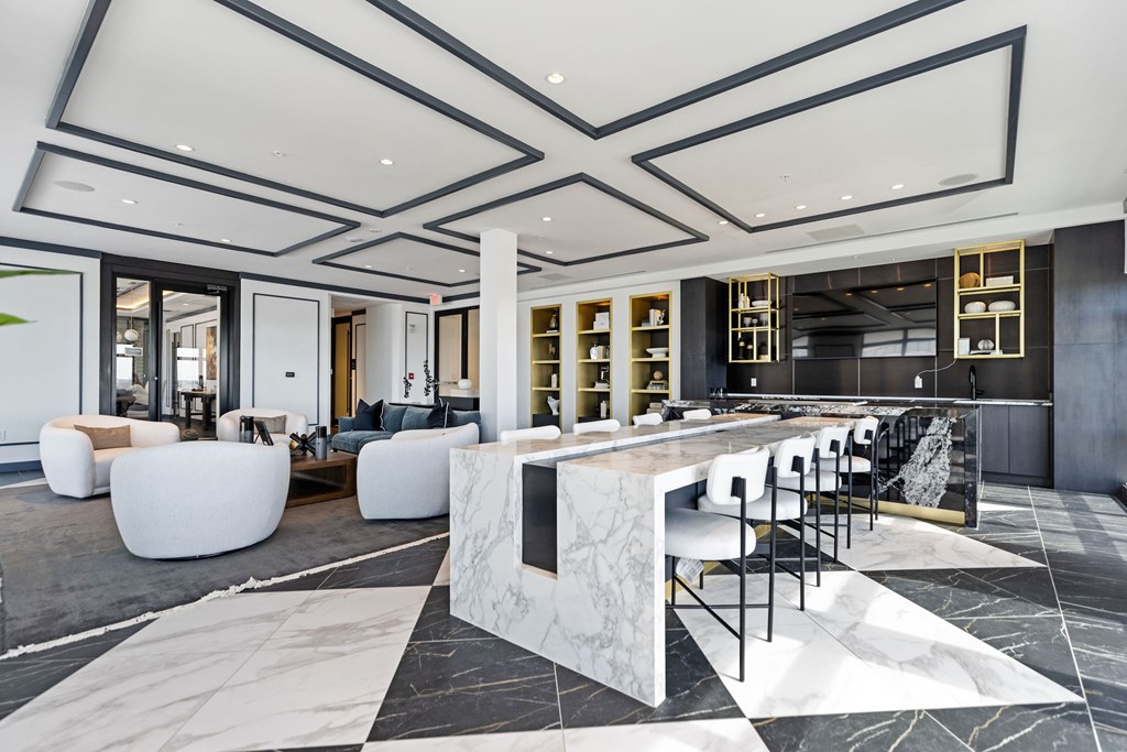A modern kitchen with a marble island and bar stools.
