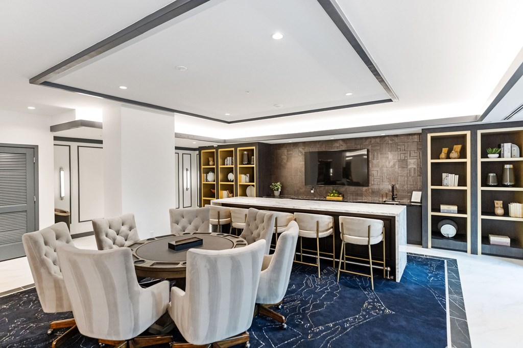 A modern dining room with a dark blue rug and white chairs.