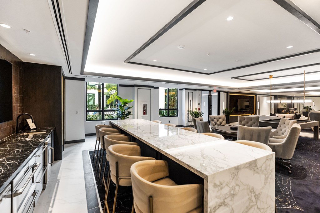 A modern kitchen with a marble island and bar stools.